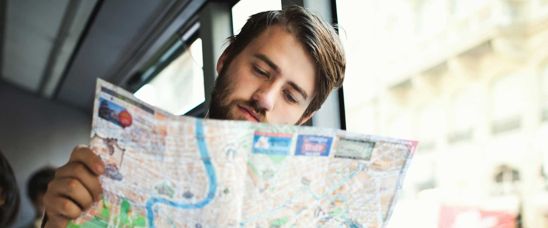 young man sitting on the bus and looking at a map